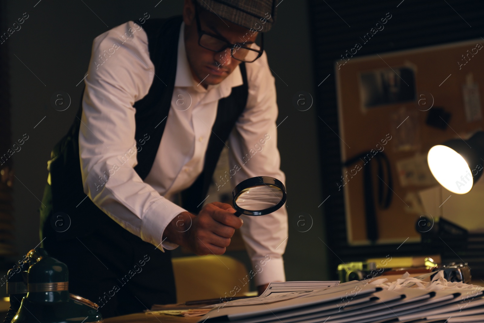Photo of Old fashioned detective with magnifying glass working in office
