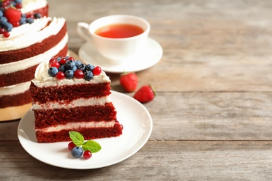 Photo of Plate with piece of delicious homemade red velvet cake and space for text on wooden table