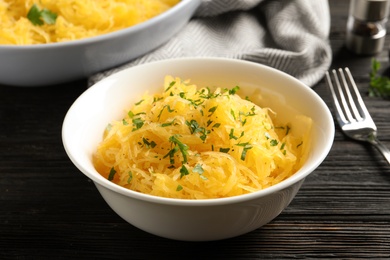 Photo of Bowl with cooked spaghetti squash on wooden table