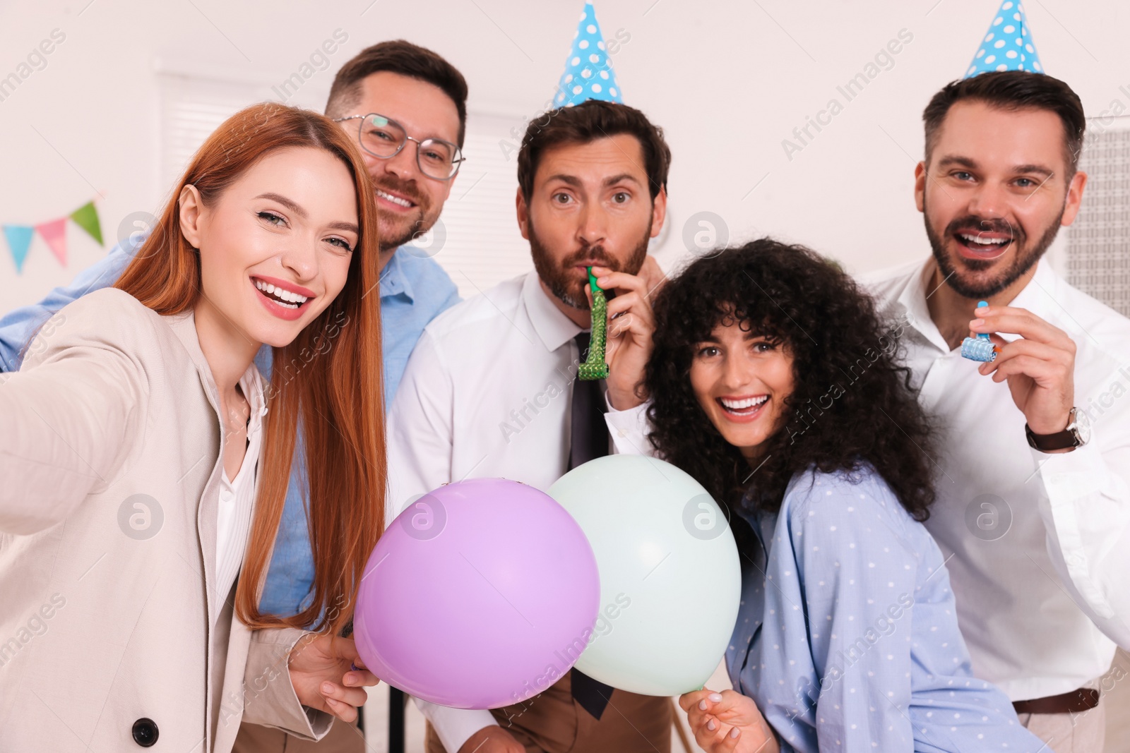 Photo of Coworkers taking selfie during office party indoors