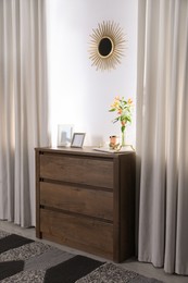Stylish room interior with wooden chest of drawers and beautiful decor elements