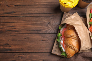 Tasty croissant sandwich on wooden table, flat lay. Space for text