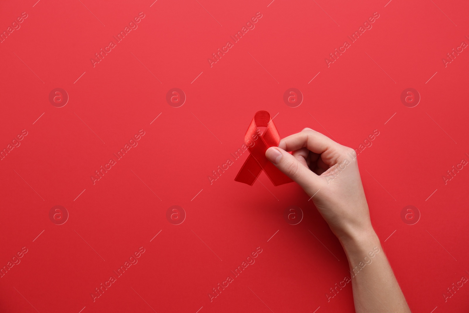 Photo of Woman holding red awareness ribbon on color background, top view with space for text. World AIDS disease day