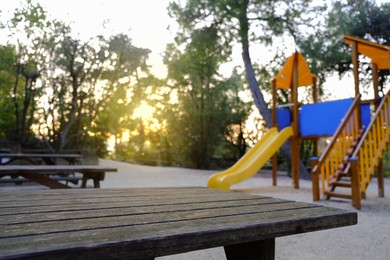 Photo of Empty playground with beautiful slide, benches and trees in park. Space for text