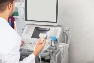 Sonographer using modern ultrasound machine in clinic, space for text