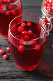 Tasty cranberry juice in glasses and fresh berries on black wooden table, closeup