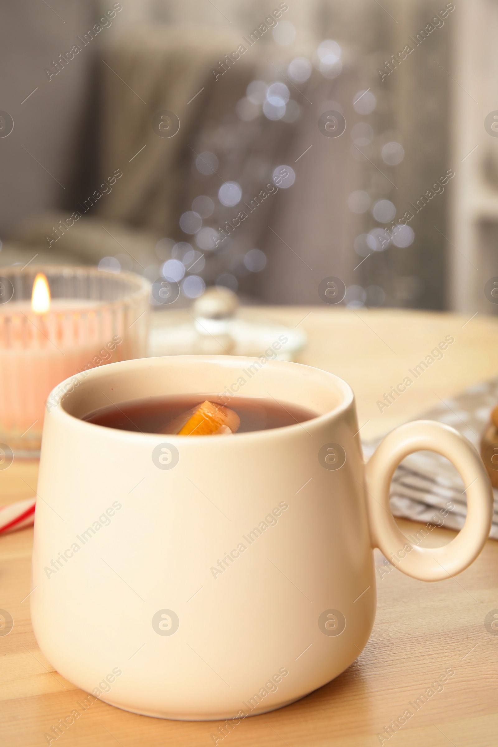 Photo of Cup of hot mulled wine on wooden table indoors. Winter drink