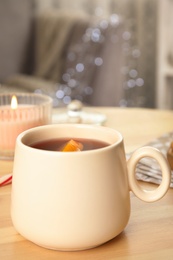 Photo of Cup of hot mulled wine on wooden table indoors. Winter drink