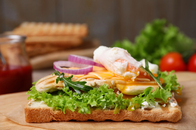 Photo of Tasty sandwich with chicken and poached egg on wooden table