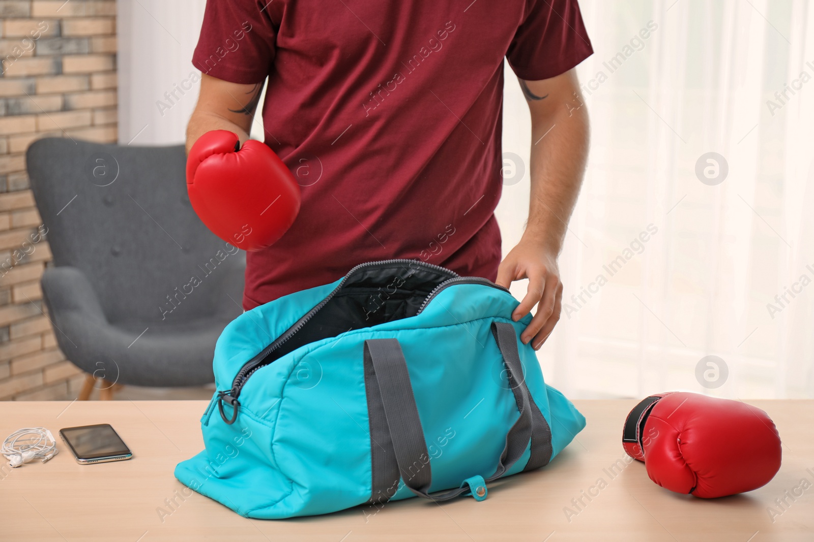 Photo of Young man packing sports bag on table