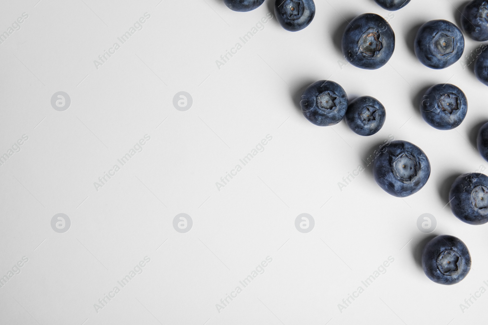 Photo of Tasty ripe blueberries on white background, flat lay