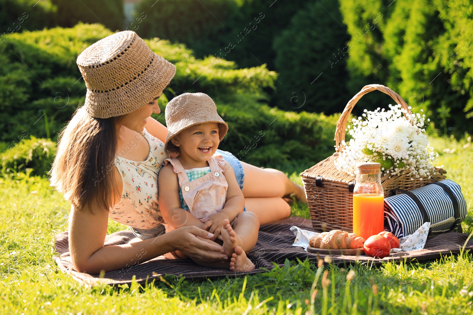 Photo of Mother with her baby daughter having picnic in garden on sunny day