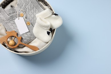 Photo of Different baby accessories and clothes in box on light blue background, top view. Space for text