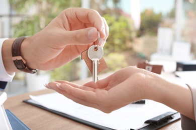 Photo of Real estate agent giving key to woman in office, closeup