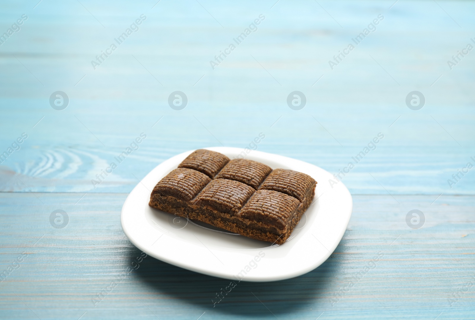 Photo of White plate with delicious and healthy hematogen bar  on blue wooden table. Space for text