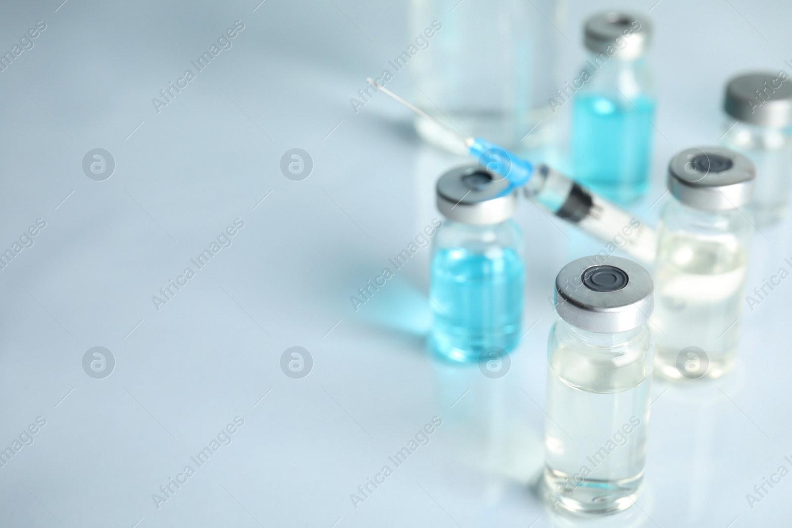 Photo of Vials and syringe on light table, space for text. Vaccination and immunization