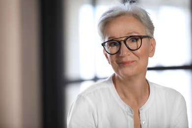 Photo of Happy mature woman in glasses indoors, space for text. Smart aging