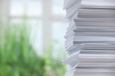 Stack of paper sheets against blurred background, closeup. Space for text