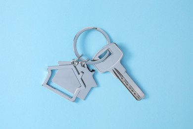 Photo of Key with keychain in shapehouse on light blue background, top view