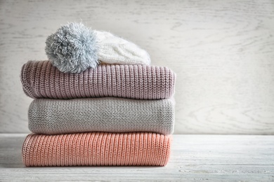 Photo of Stack of warm knitted clothes on table