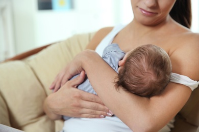 Photo of Young woman breastfeeding her baby at home, closeup