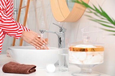 Photo of Woman washing hands over sink in bathroom, closeup