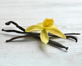 Photo of Vanilla sticks and flower on wooden background