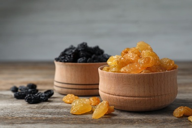 Photo of Bowls with raisins on wooden table. Dried fruit as healthy snack