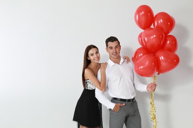 Photo of Beautiful couple with heart shaped balloons on light background