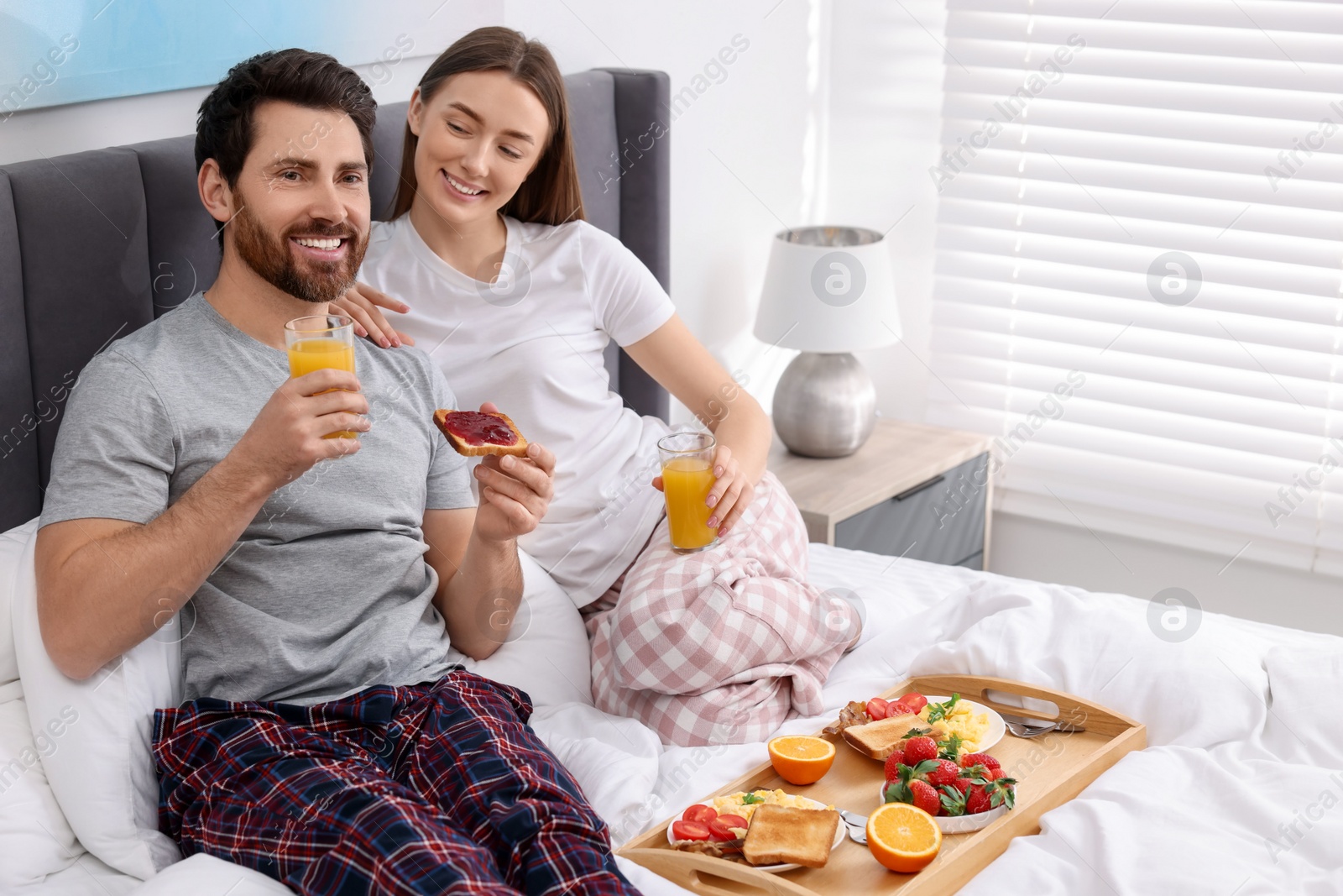 Photo of Happy couple having breakfast in bedroom. Space for text