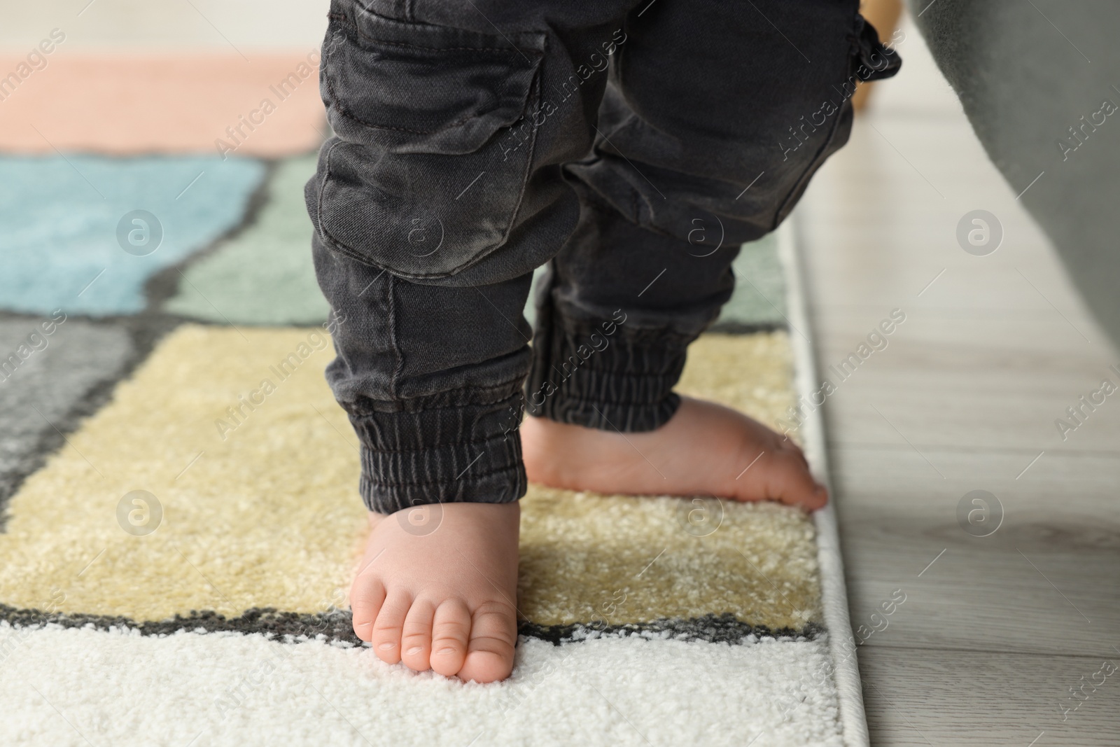 Photo of Baby standing on soft carpet, closeup view