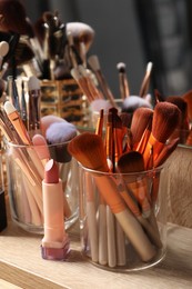 Photo of Setprofessional brushes and makeup products near mirror on wooden table