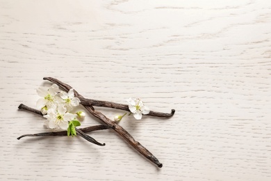 Photo of Vanilla sticks and flowers on wooden background