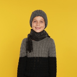 Photo of Cute little boy in warm clothes on yellow background. Winter season