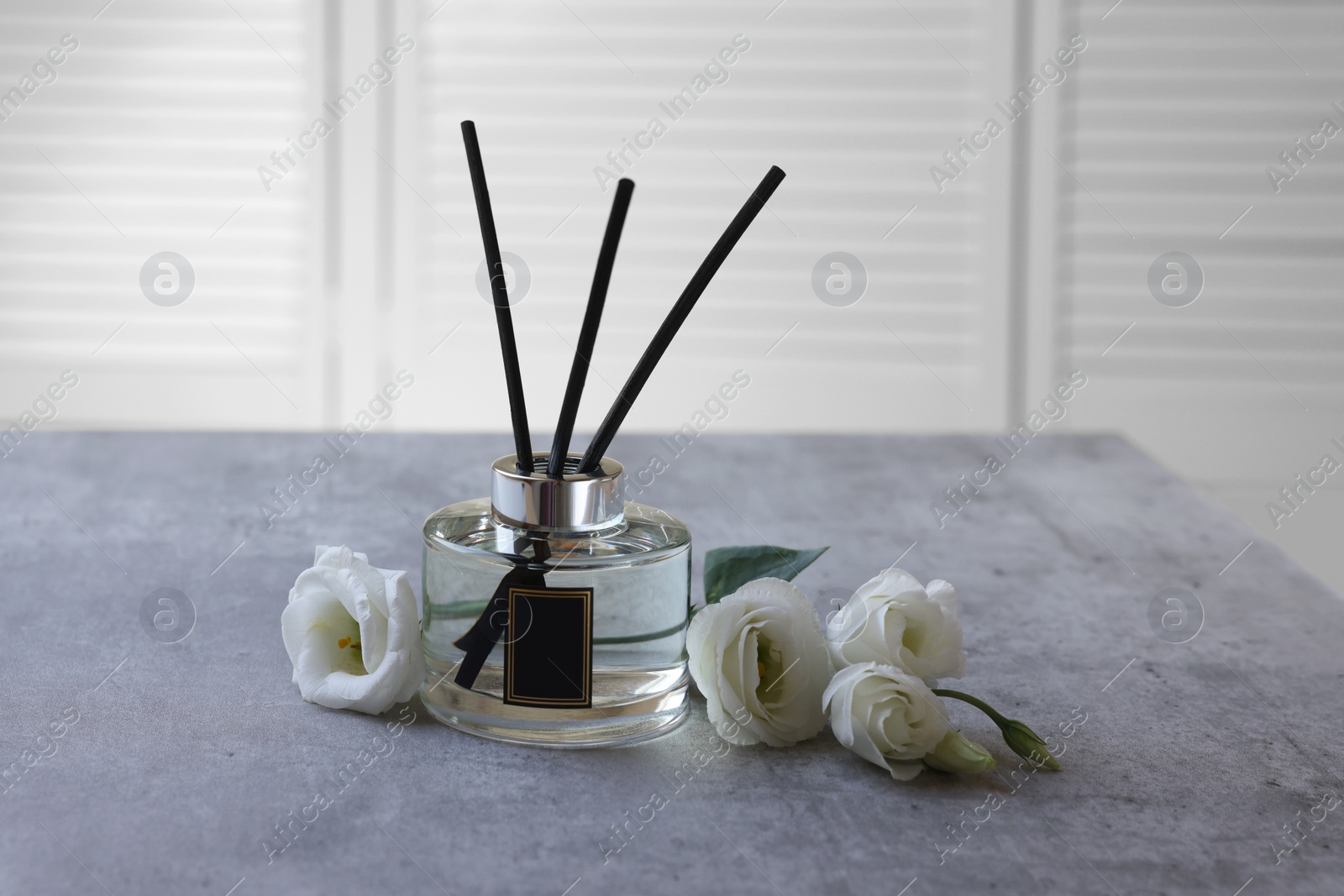 Photo of Reed diffuser and eustoma flowers on gray marble table