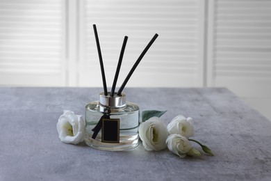 Reed diffuser and eustoma flowers on gray marble table