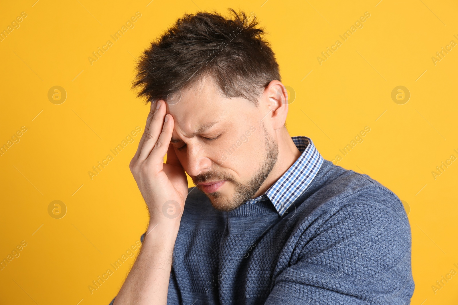 Photo of Man suffering from terrible migraine on yellow background