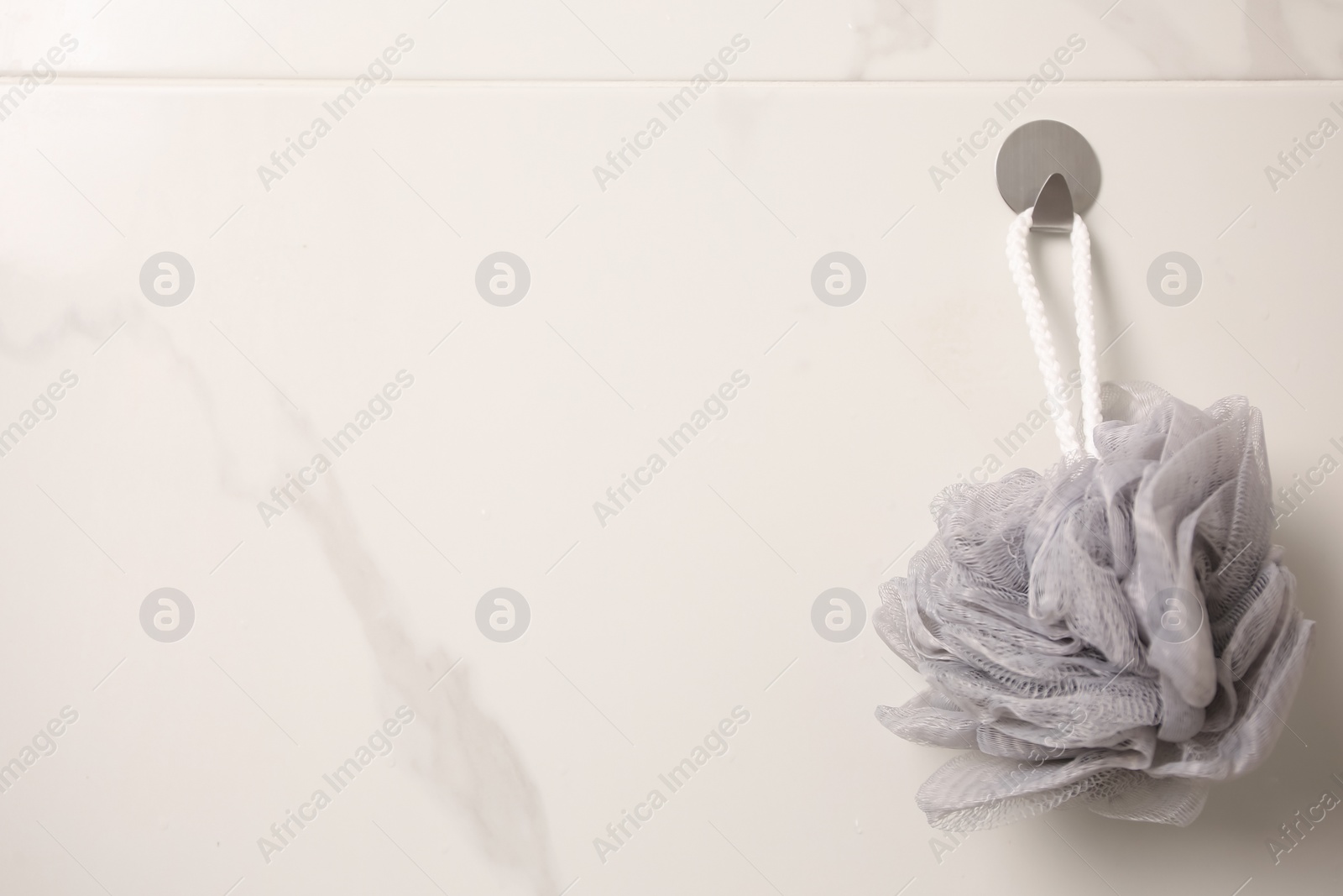 Photo of Grey shower puff hanging in bathroom, space for text