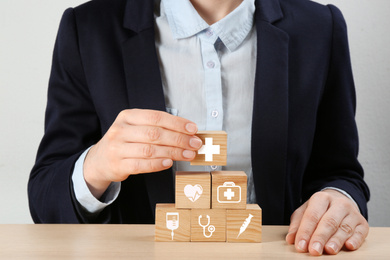 Image of Woman building pyramid at wooden table, closeup. Health insurance concept