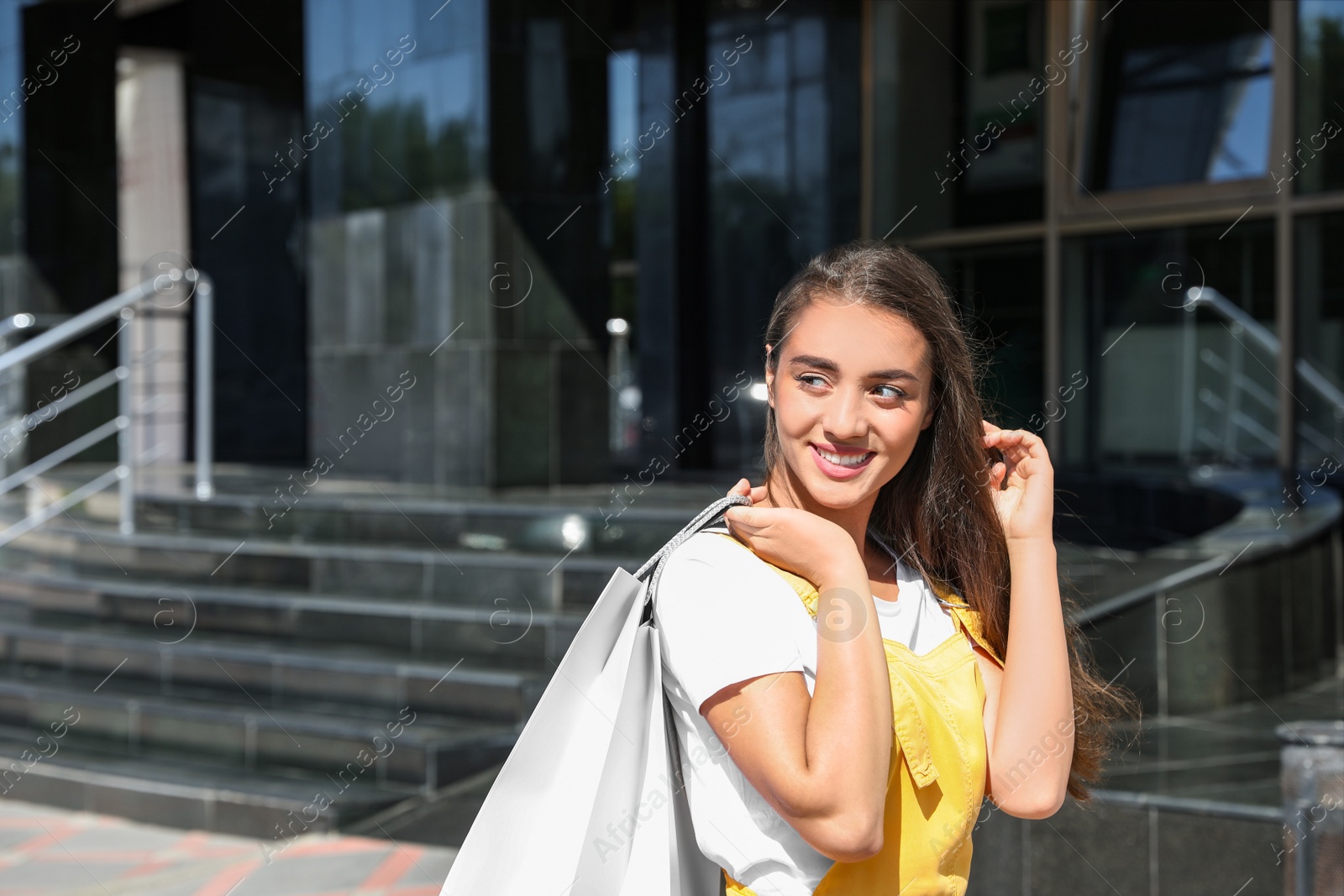 Photo of Happy young woman with shopping bags outdoors