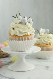 Photo of Tasty Easter cupcakes with vanilla cream on white marble table