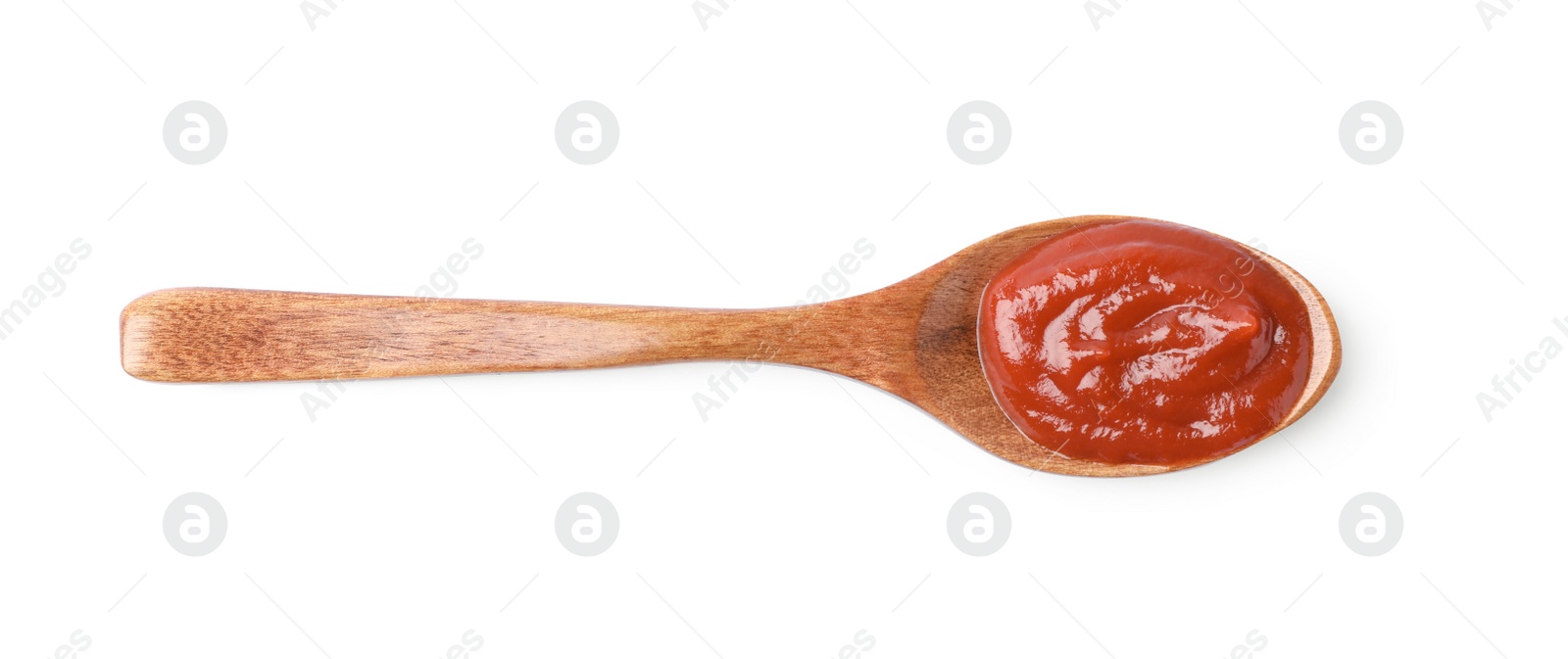 Photo of Ketchup in wooden spoon isolated on white, top view