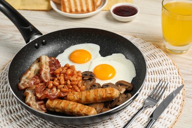 Photo of Frying pan with cooked traditional English breakfast on white table, closeup