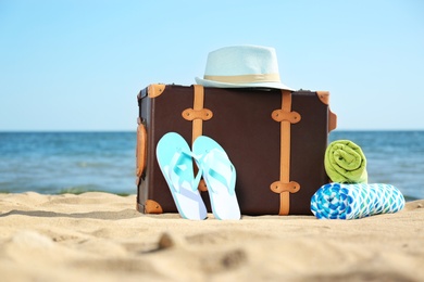 Photo of Suitcase and beach accessories on sand near sea. Space for text