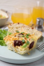 Photo of Tasty sausage casserole with green onion on light grey table, closeup