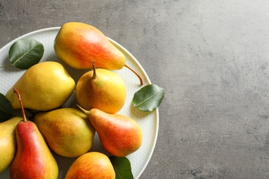 Photo of Plate with ripe pears on grey background, top view. Space for text