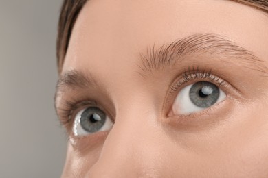 Photo of Woman with beautiful natural eyelashes on grey background, closeup