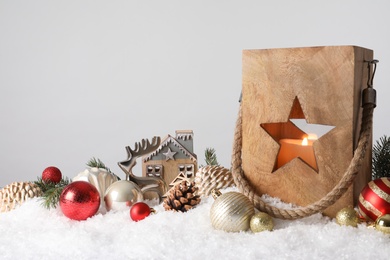 Photo of Composition with wooden Christmas lantern on snow against light grey background, space for text