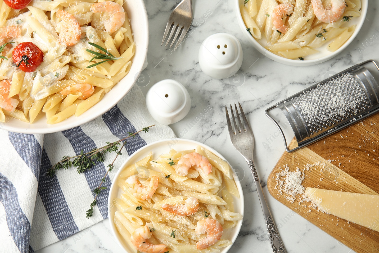 Photo of Delicious pasta with shrimps served on white marble table, flat lay