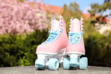 Photo of Stylish pink roller skates outdoors on sunny day